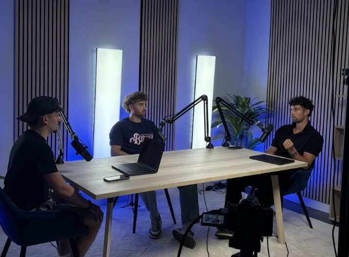 Plateau de tournage podcast à trois intervenants, éclairage bleu et caméra sur trépied